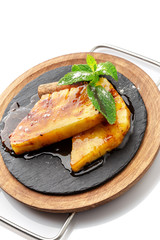 Pieces of pineapple with mint, poured with caramel for dessert.