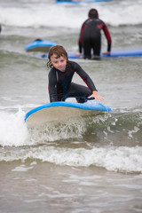 Little boy learning to surf at the beach, getting up on surfboard for the first time, west coast of Ireland