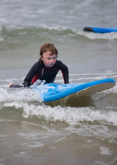 Obraz premium Little boy learning to surf at the beach, getting up on surfboard for the first time, west coast of Ireland
