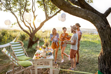 Group of a young and happy friends having fun during a festive picnic in the beautifully decorated...