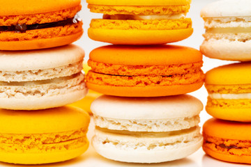 Orange and yellow macarons or macaroons stacked or piled. Closeup.
