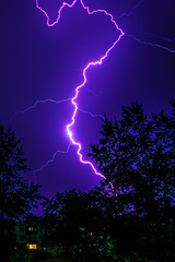bright flashes of lightning during night thunderstorms, silhouettes of trees and houses against the...