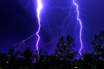 bright flashes of lightning during night thunderstorms, silhouettes of trees and houses against the...