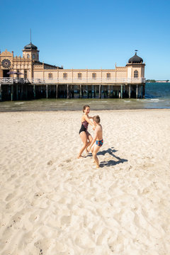 Summer seaview of two children playing on the beach in front of the famous old historic wooden bathhous Varbergs Kallbadhus. A cold water public bath located in the ocean in Sweden.