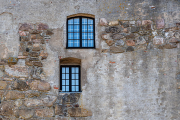 Horizontal frame of two windows on an old rough acient medieval stone wall at Varberg Fortress in Sweden.