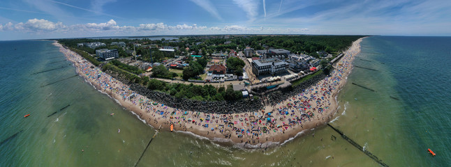 Drone aerial perspective and panoramic view on sunny beach with sunbathers with windbreaks and...