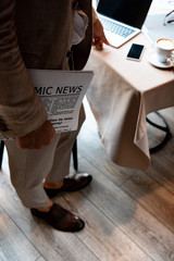 cropped view of businessman holding newspaper in cafe