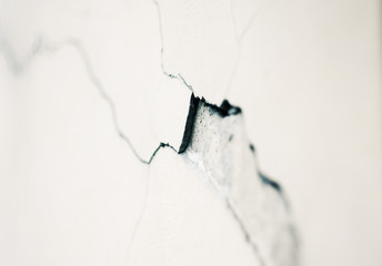 Abstract background depicting a deep curved crack in the plaster on a white smooth wall.