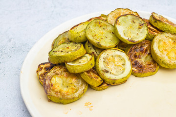 Baked roasted zucchini slices on plate. White background.