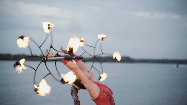 Girl with a torch fire show on the river bank at sunset. slow motion