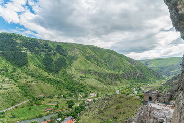 Fototapeta premium Panoramic view of Vardzia cave monastery town. View from the monastery to the river valley and green slopes on a sunny summer day