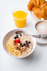 Breakfast with oatmeal with berries and nuts, coffee and orange juice