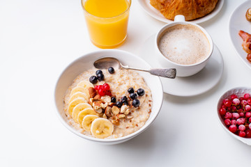 Breakfast with oatmeal with berries and nuts, coffee and orange juice
