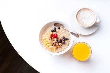 Breakfast with oatmeal with berries and nuts, coffee and orange juice