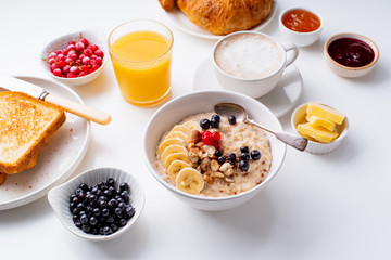 Breakfast with oatmeal with berries and nuts, croissants, toasts with jam and butter, coffee and orange juice
