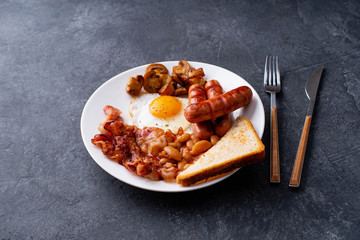 Top view flatlay with classical english breakfast with fried bacon, mushrooms and eggs. Served with black coffee.