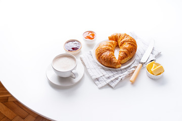 Top view flatlay with fresh croissants served with jams, coffee and buter. Morning meal concept. White background