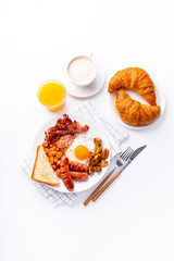 Top view flatlay with classical english breakfast with fried bacon, mushrooms and eggs. Served with orange juice, coffee and croissants. Copy space, white background
