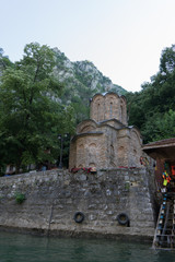 Small orthodox church with old brick walls under the mountain with trees and big forest. River with religious attraction in Matka Canyon, Macedonia