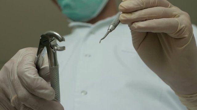 close-up of a dentist holding a tooth extraction tool dentistry sterile gloves tooth extraction teeth treatment hands and instrument in focus