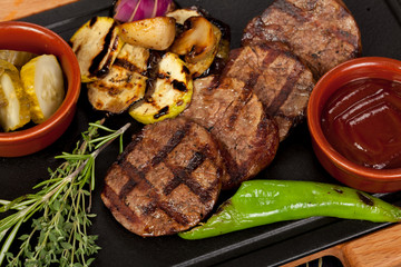 juicy, fried, tender steak with vegetables and sauces on a special stand