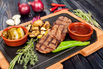 juicy, fried, tender steak with vegetables and sauces on a special stand