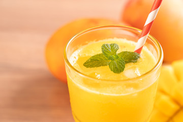 Fresh mango juice with beautiful chopped pulp flesh on bright wooden table background. Tropical fruit drink design concept. Close up, copy space.