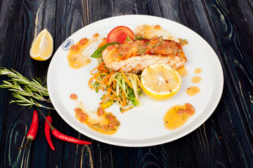 appetizing fried fish, beautifully laid out with greens and vegetables on a dish, for designer solutions in cooking