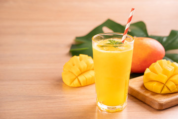 Fresh mango juice with beautiful chopped pulp flesh on bright wooden table background. Tropical...