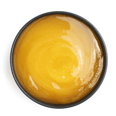 Thick honey in dark bowl on white background. Top view