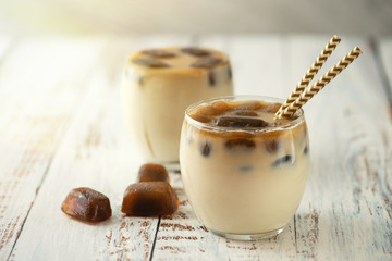 Milk coffee cocktail in glasses with frozen coffee cubes on light wooden table. Side view