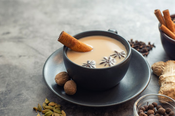 Cup of traditional indian masala chai tea with ingredients: cinnamon, cardamom, anise, nutmeg