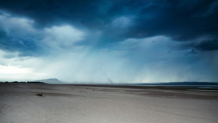 Fototapeta na wymiar Sandy beach before the storm, it is raining and thunderclouds