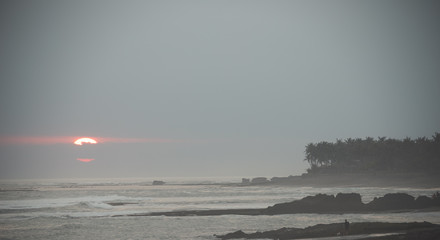 big sun peaking thought the clouds at Pererenan Beach bali at sunset