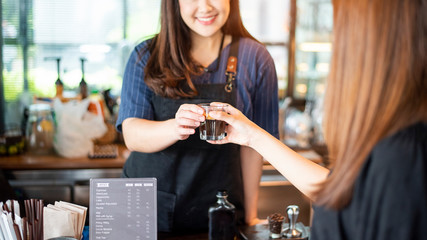 Close up of female hand is taking hot coffee from Barista
