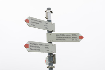 Obraz premium direction sign in the mountains with a whitee misty sky.