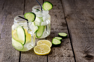 Glass Jar Mug of Water with Lemon and Cucumber on Wooden Background Infused Water Detox Drink