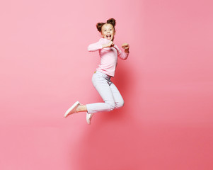  funny child girl dressed casual jumping on pink  background 
