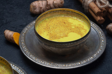 Golden turmeric milk on the black background with ingredients