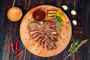 juicy, fried, tender steak with vegetables and sauces on a special stand