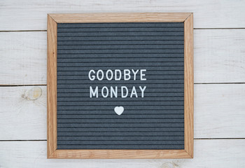 text in English goodbye Monday on a felt letter Board in gray . top view on white wooden background