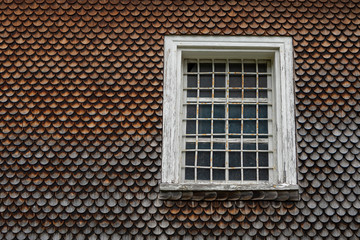 grey weathered wooden shingles on an traditional alpine roof with a wooden window