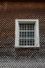grey weathered wooden shingles on an traditional alpine roof with a wooden window