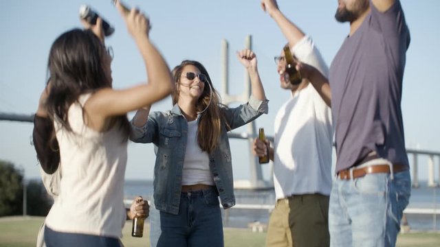 Laughing company jumping with beer bottle. Smiling young friends having fun together. Leisure concept
