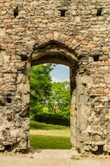 Panensky Tynec, Czech Republic - July 15 2019: Stone wall with portal into a garden with green trees and grass, as a part of ruin of the unfinished Gothic church of the Virgin Mary from 14th century. 