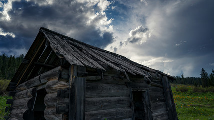 A collapsed wooden old hut in the background of a cloud