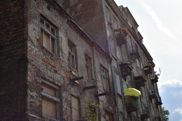 Facade of old slum house with damaged brick walls, balconies decorated with flowers, in a poor and criminal district. Location: Praga district of Warsaw city, Poland - 282630575