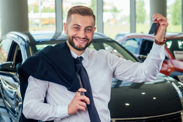 Smiling well-dressed man posing near a car at showroom