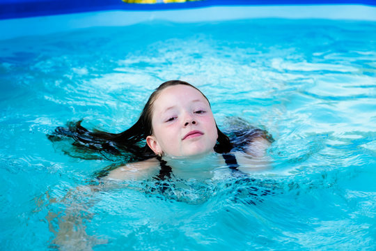 Girl is swimming in the pool in summer