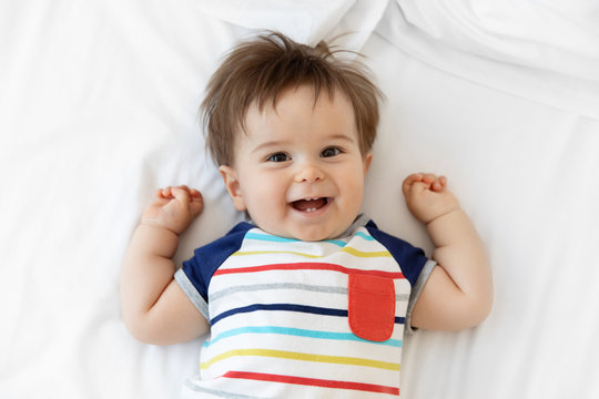Portrait of smiling baby lying on white bed